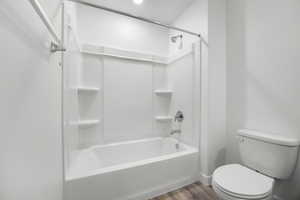 Bathroom with hardwood / wood-style floors,  shower combination, and toilet