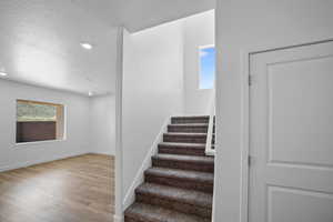 Stairway featuring hardwood / wood-style floors and a textured ceiling