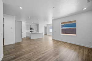 Unfurnished living room featuring sink, a textured ceiling, and light hardwood / wood-style floors