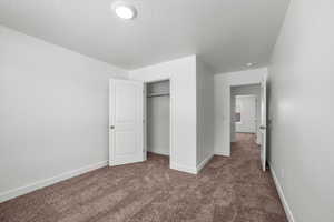 Unfurnished bedroom featuring carpet floors, a textured ceiling, and a closet