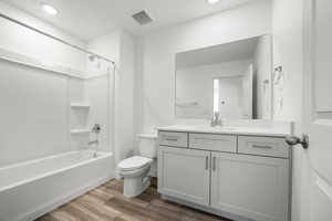 Full bathroom featuring wood-type flooring, vanity, washtub / shower combination, and toilet