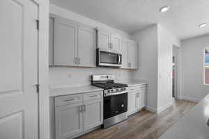 Kitchen with stainless steel appliances, dark hardwood / wood-style flooring, and a textured ceiling