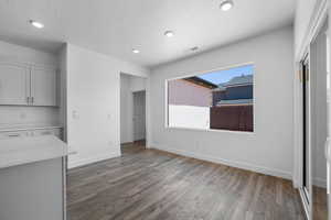 Unfurnished dining area with dark wood-type flooring and a textured ceiling