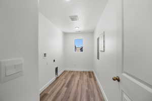 Washroom with hookup for a washing machine, wood-type flooring, hookup for an electric dryer, and a textured ceiling