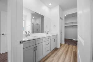 Bathroom with vanity, a shower with shower door, and wood-type flooring