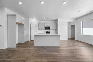 Kitchen with sink, stainless steel appliances, dark hardwood / wood-style flooring, and a kitchen island with sink