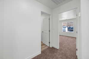 Hallway featuring light carpet and a textured ceiling