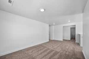 Carpeted empty room featuring a textured ceiling