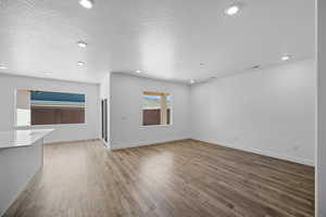 Unfurnished living room with hardwood / wood-style floors and a textured ceiling