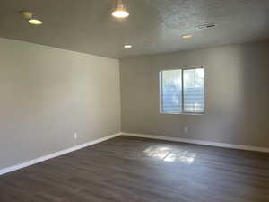 Empty room featuring dark wood-type flooring and a textured ceiling