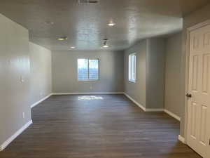 Unfurnished room featuring dark hardwood / wood-style flooring and a textured ceiling