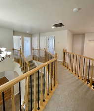 Hallway featuring light carpet