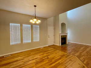 Unfurnished living room featuring wood-type flooring and an inviting chandelier