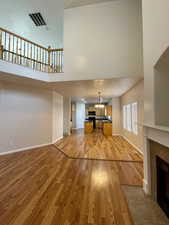 Unfurnished living room featuring a high ceiling, a tile fireplace, and light hardwood / wood-style flooring