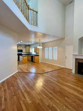 Unfurnished living room with a notable chandelier, hardwood / wood-style flooring, a tile fireplace, and a towering ceiling
