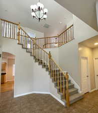 Staircase with a towering ceiling, tile patterned floors, and a chandelier