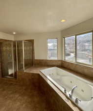 Bathroom featuring separate shower and tub, tile patterned floors, and a textured ceiling