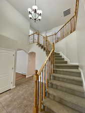 Stairway featuring a towering ceiling, tile patterned floors, and a chandelier