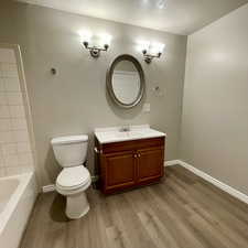 Bathroom featuring hardwood / wood-style flooring, vanity, toilet, and a textured ceiling