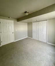 Unfurnished bedroom featuring a closet, a textured ceiling, and dark colored carpet