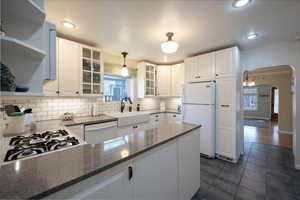 Kitchen with large double sink, appliances, custom cabinetry. Quartz countertops, decorative light fixture as well as recessed lighting.