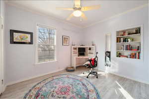 Bedroom space featuring built in bookcase, crown molding, hardwood-type flooring.