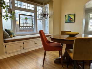 Dining space with natural light, window seat and hardwood flooring.