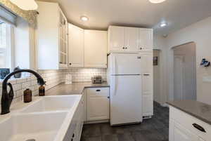 Kitchen features a large double sink, white cabinetry, tiled backsplash, Quartz Counters, tile flooring.