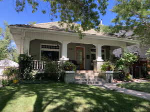 Summer view of home  with a large porch and front lawn.