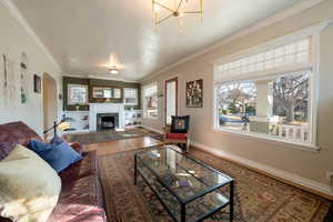 View of living room and sitting room  adjoining  each other,  hardwood floors, crown molding, and a wealth of natural light.