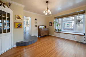 Dining room with lovely window seat  crown molding, hardwood  flooring, built-in hutch.