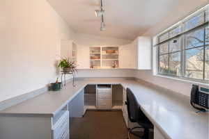 Office off of mudroom featuring custom built-ins, ample counter space, light and bright office space, track lighting,