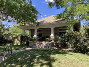 Summer view of front of home featuring  front lawn and large porch.