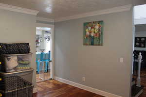 Hallway with crown molding, hardwood / wood-style floors, and a textured ceiling