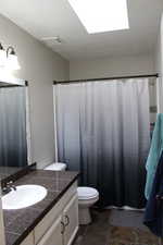 Main bathroom with vanity, a skylight, and toilet