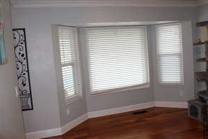 Unfurnished living room featuring ornamental molding and dark wood-type flooring