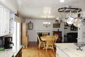 Dining room with an inviting chandelier, light hardwood / wood-style flooring, and a textured ceiling