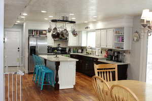 Kitchen with stainless steel fridge, dishwasher, electric range, a center island, and light stone counters