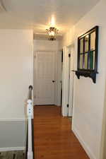 Corridor with dark hardwood / wood-style floors and a textured ceiling