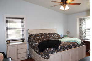 Bedroom with dark wood-type flooring, ceiling fan, and vaulted ceiling