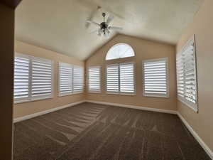 Living room with lofted ceiling, new carpet, ceiling fan, window shutters and wealth of natural light