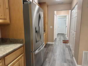 Kitchen with stainless steel refrigerator with ice dispenser, new wood-type flooring, and a textured ceiling