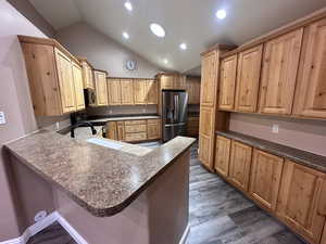 Kitchen with lofted ceiling, a breakfast bar, dark hardwood / new wood-style flooring, kitchen peninsula, and new bluetooth stainless steel appliances