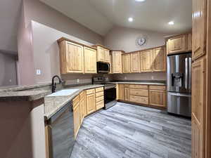 Kitchen with sink, new wood-style flooring, bluetooth stainless steel appliances and vaulted ceiling