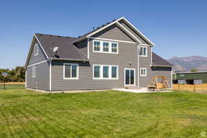 Back of house with a mountain view, a lawn, and a patio area