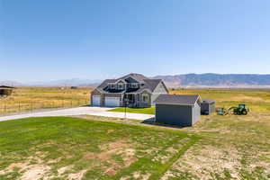 View of front of property featuring a garage, a mountain view, a rural view, and a front lawn