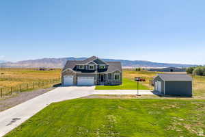 View of front of home with a rural view, a mountain view, and a front lawn