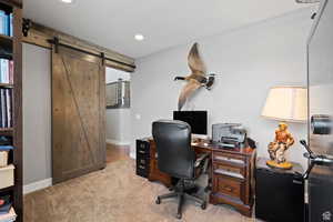 Office area with a barn door and light colored carpet