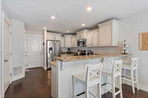 Kitchen with granite counters, dark hardwood flooring, a kitchen peninsula, and stainless steel appliances