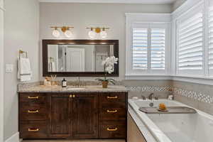 Bathroom with vanity and tiled bath